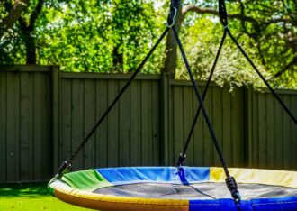 Saucer swing hanging over an artificial grass backyard lawn