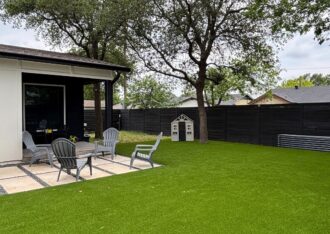 Artificial grass backyard with patio chairs and shade trees