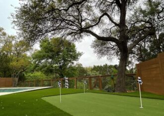 Backyard putting green set into an artificial grass lawn near a pool