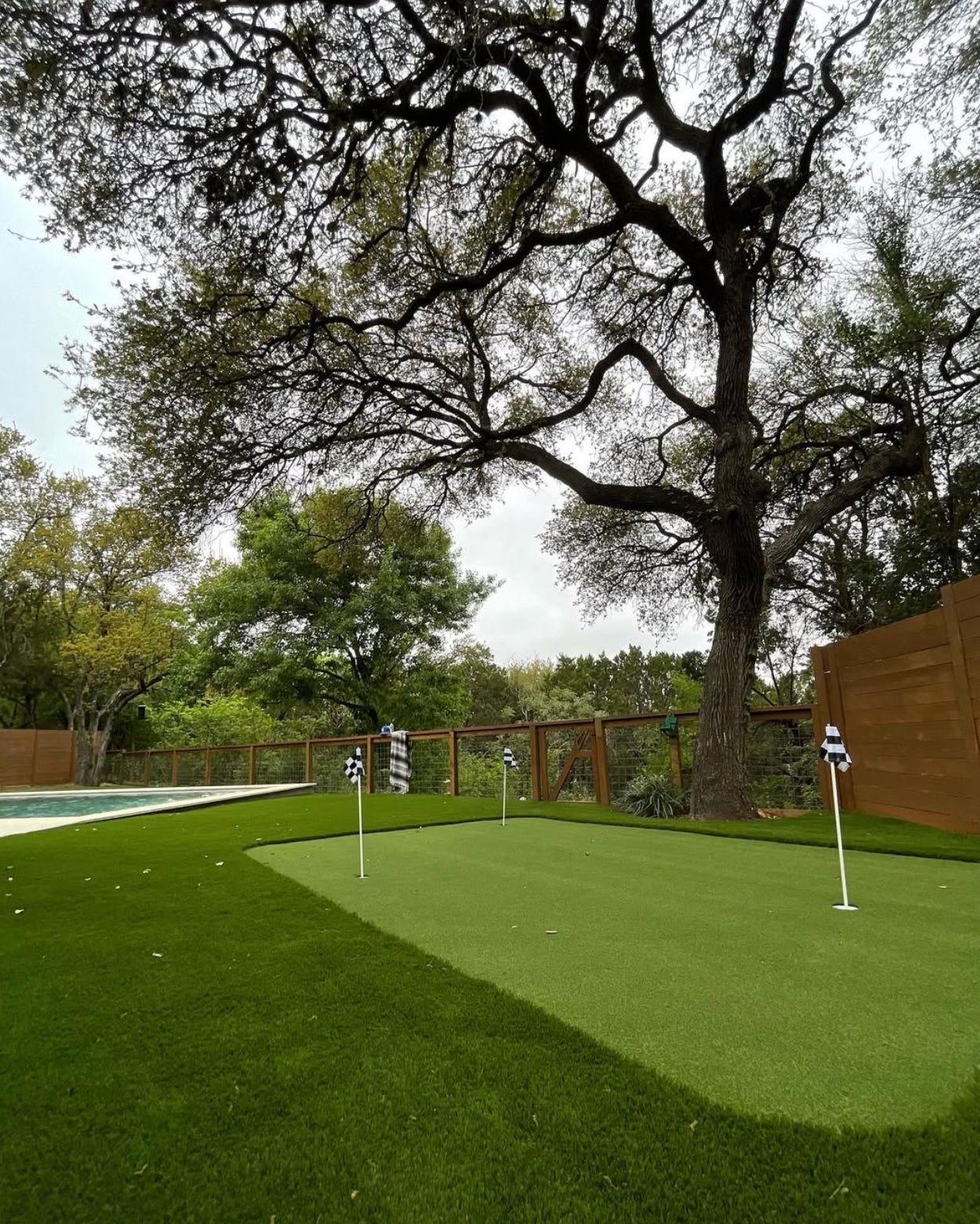 Backyard putting green set into an artificial grass lawn near a pool